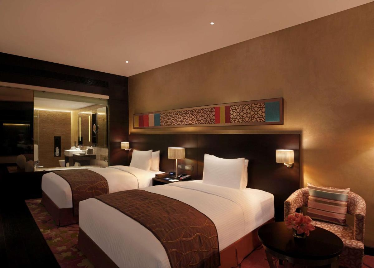 a hotel room with two beds and a bathroom at Hilton Jaipur in Jaipur a hotel room with two beds and a bathroom at Hilton Jaipur in Jaipur