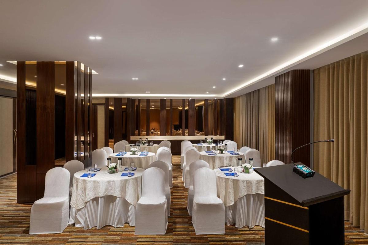 a conference room with white tables and chairs and a podium at Hilton Jaipur in Jaipur a conference room with white tables and chairs and a podium at Hilton Jaipur in Jaipur