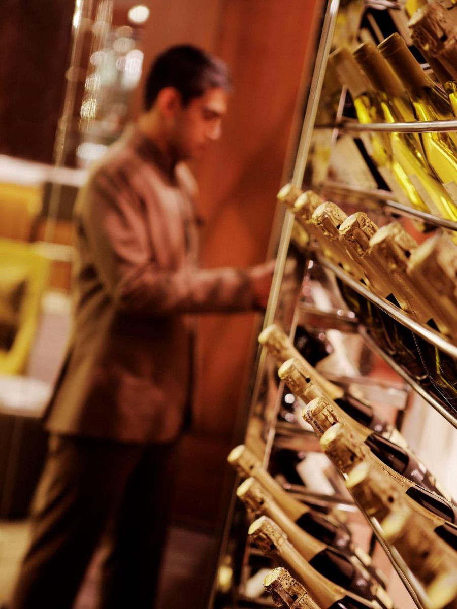 a man standing in front of a shelf of wine bottles at Hilton Jaipur in Jaipur a man standing in front of a shelf of wine bottles at Hilton Jaipur in Jaipur
