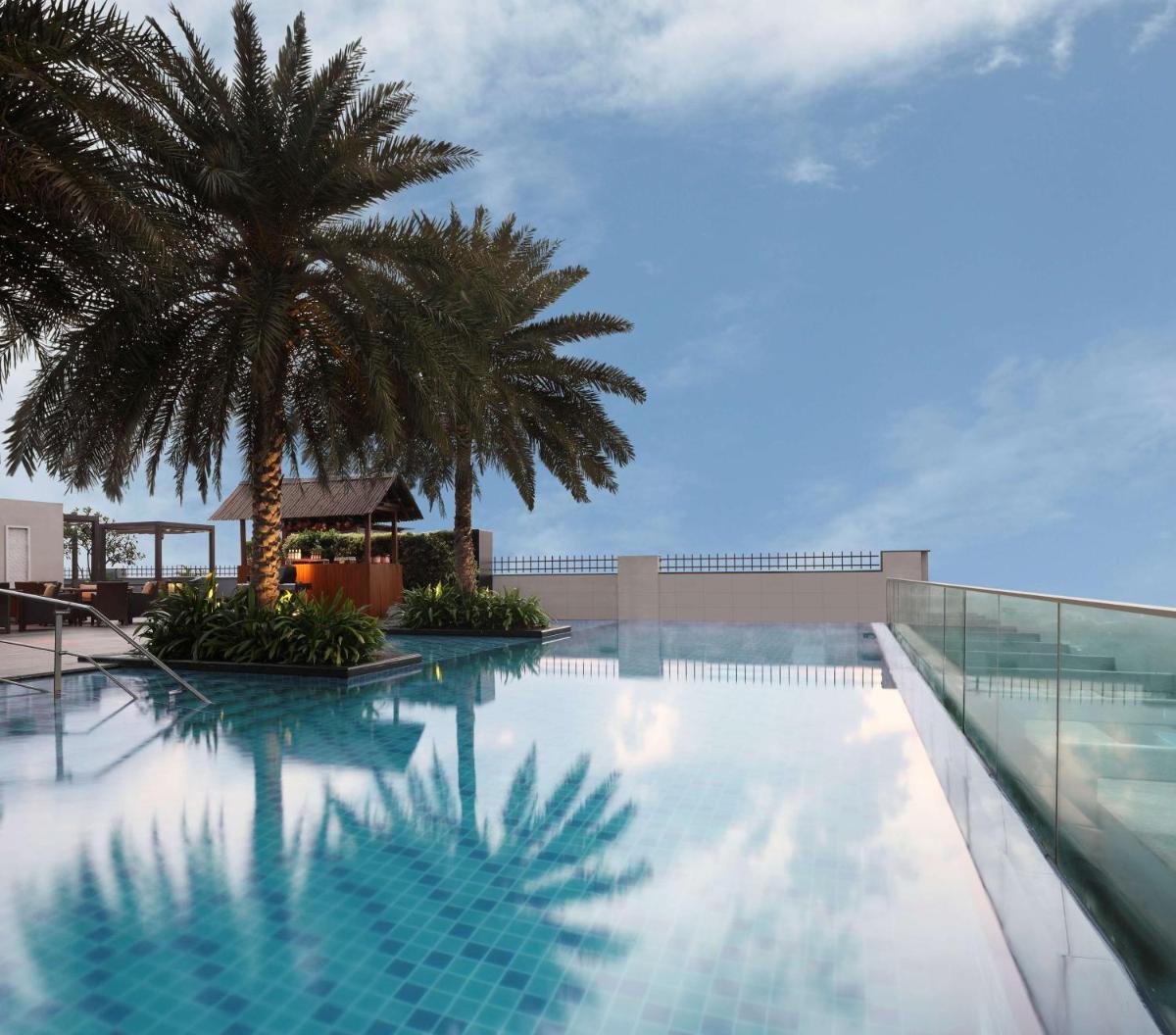 a swimming pool with a palm tree on a building at Hilton Chennai in Chennai