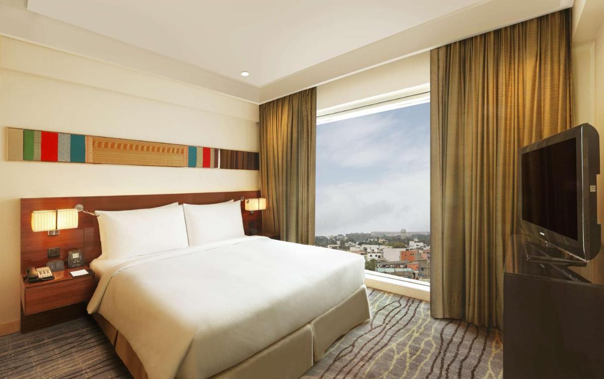 a hotel room with a bed and a large window at Hilton Chennai in Chennai