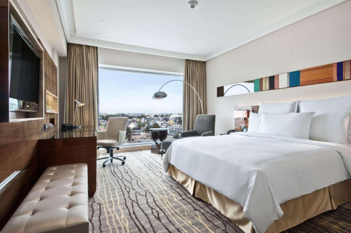 a hotel room with a bed and a large window at Hilton Chennai in Chennai
