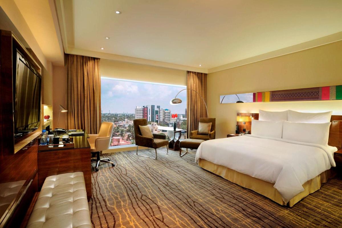 a hotel room with a large bed and a desk at Hilton Chennai in Chennai