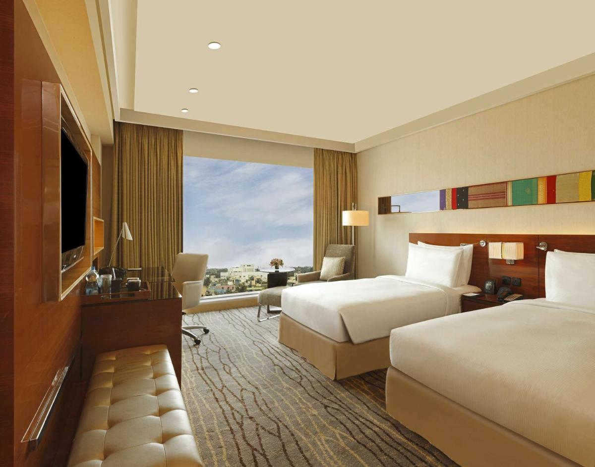 a hotel room with two beds and a large window at Hilton Chennai in Chennai