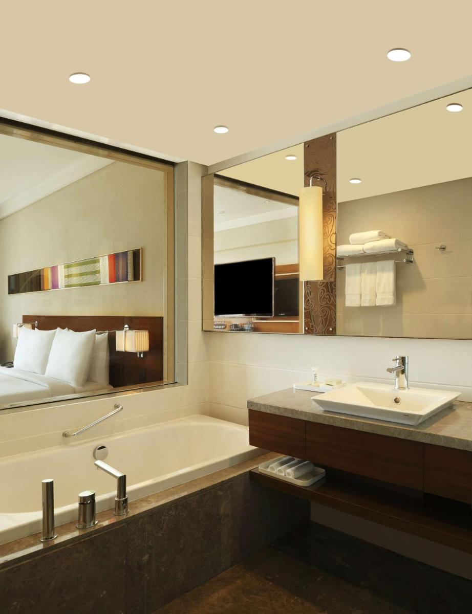 a bathroom with a tub and a sink and a mirror at Hilton Chennai in Chennai