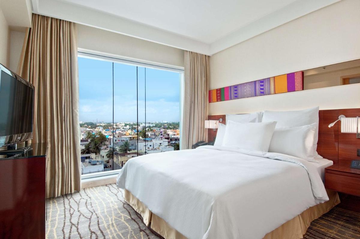 a bedroom with a large bed and a large window at Hilton Chennai in Chennai
