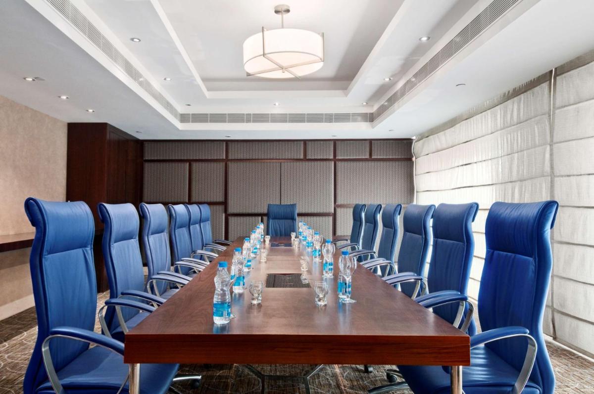 a conference room with a long table and blue chairs at Hilton Chennai in Chennai