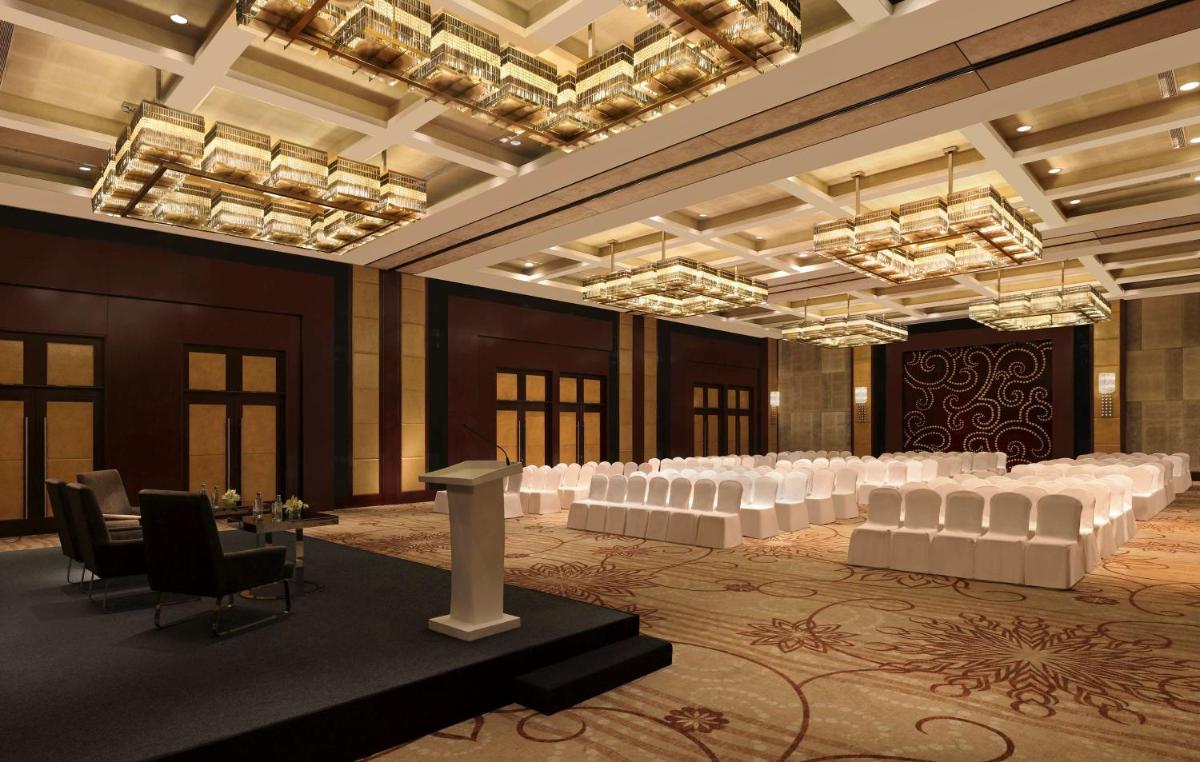 a banquet hall with white tables and chairs and chandeliers at Hilton Chennai in Chennai