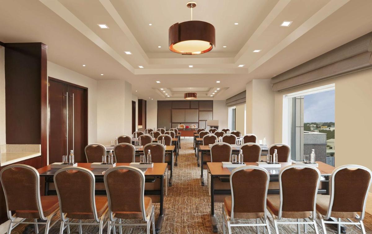 a conference room with tables and chairs and a large window at Hilton Chennai in Chennai