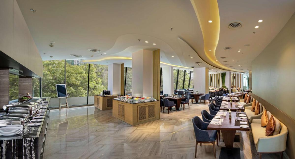 a restaurant with long tables and chairs and windows at DoubleTree by Hilton Ahmedabad in Ahmedabad