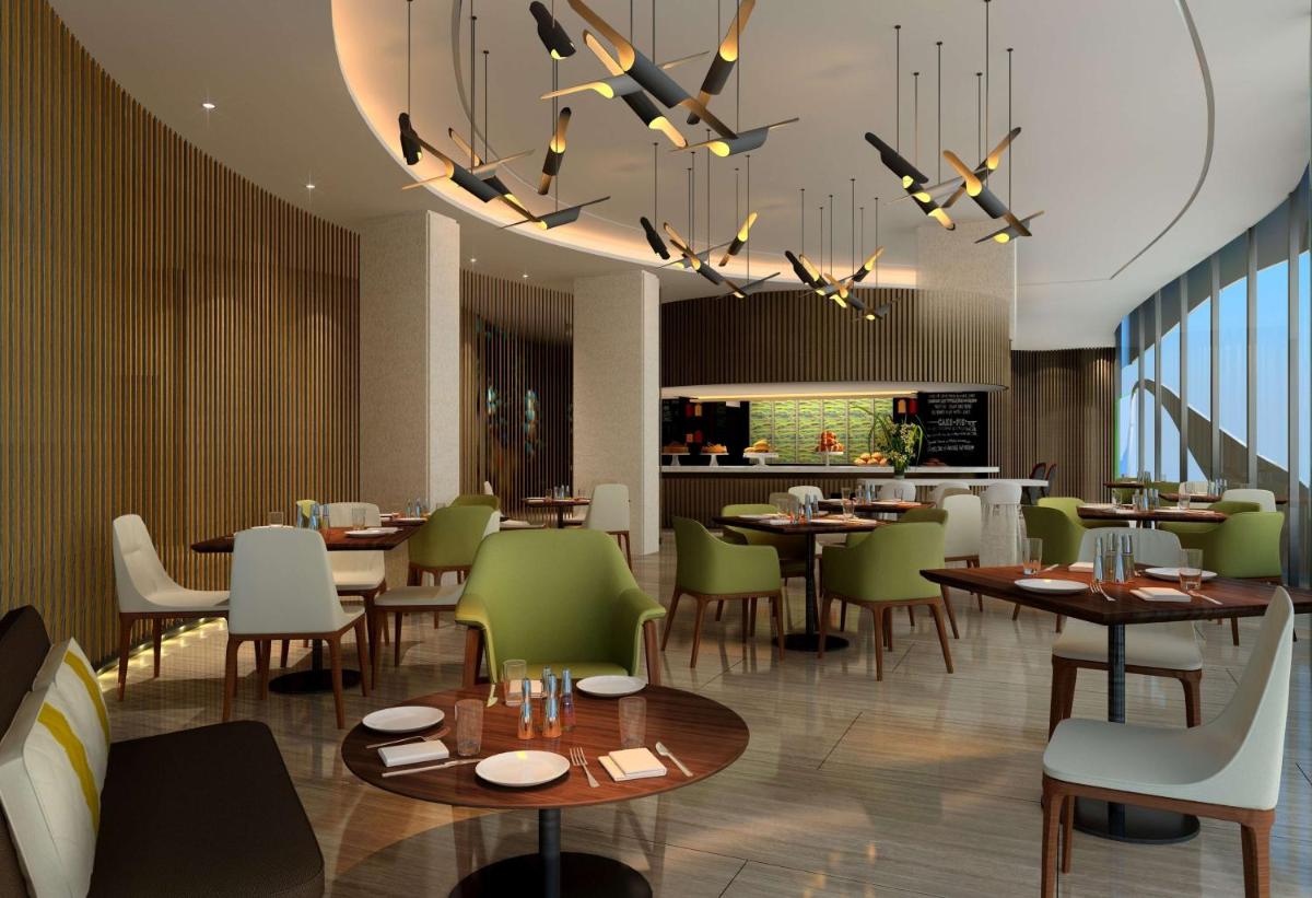 a restaurant with tables and green chairs and a chandelier at DoubleTree by Hilton Ahmedabad in Ahmedabad