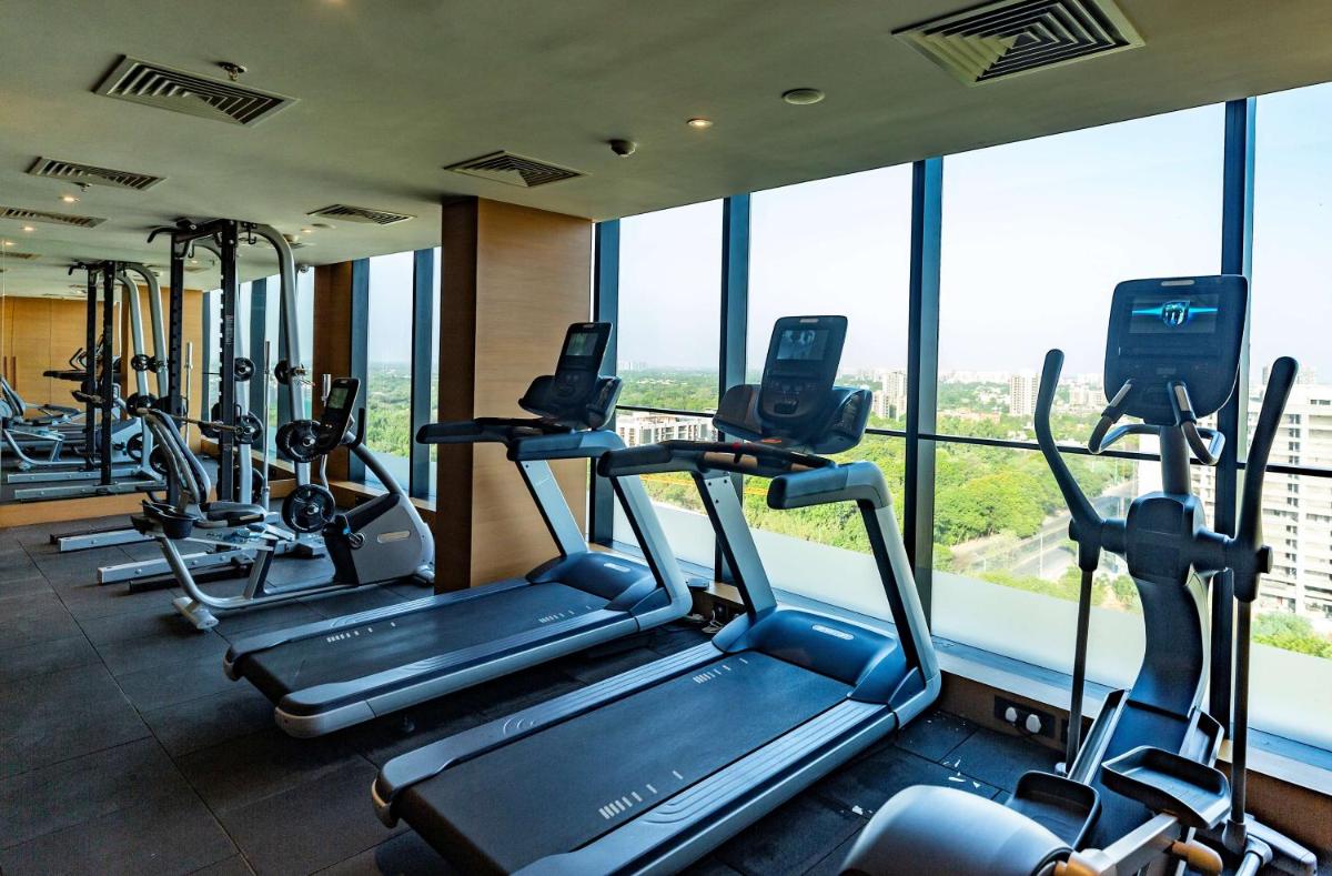 a gym with several tread machines in a building with windows at DoubleTree by Hilton Ahmedabad in Ahmedabad