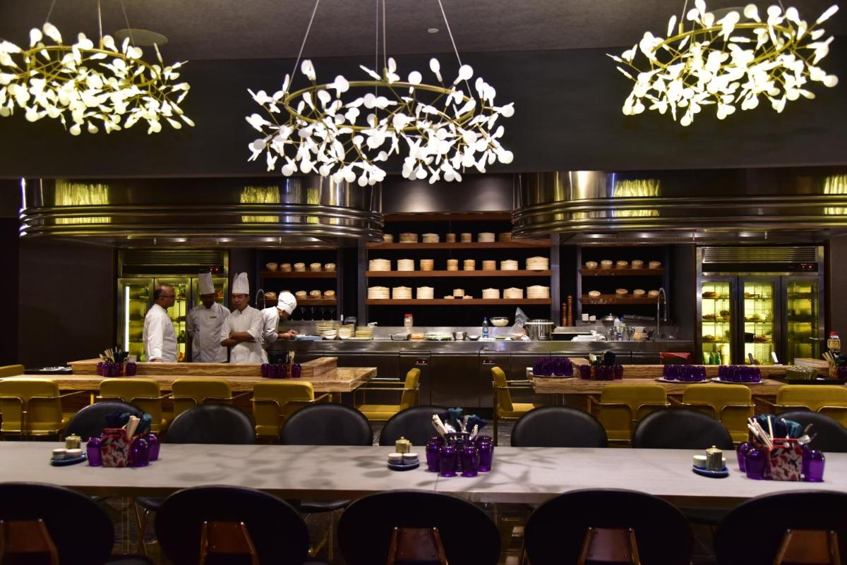 a restaurant with tables and chefs in the background at Park Hyatt Hotel and Residences, Hyderabad in Hyderabad