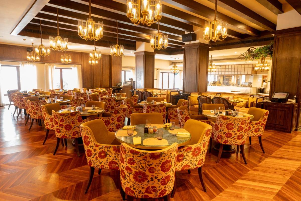 a dining room with tables and chairs and chandeliers at President - IHCL SeleQtions in Mumbai