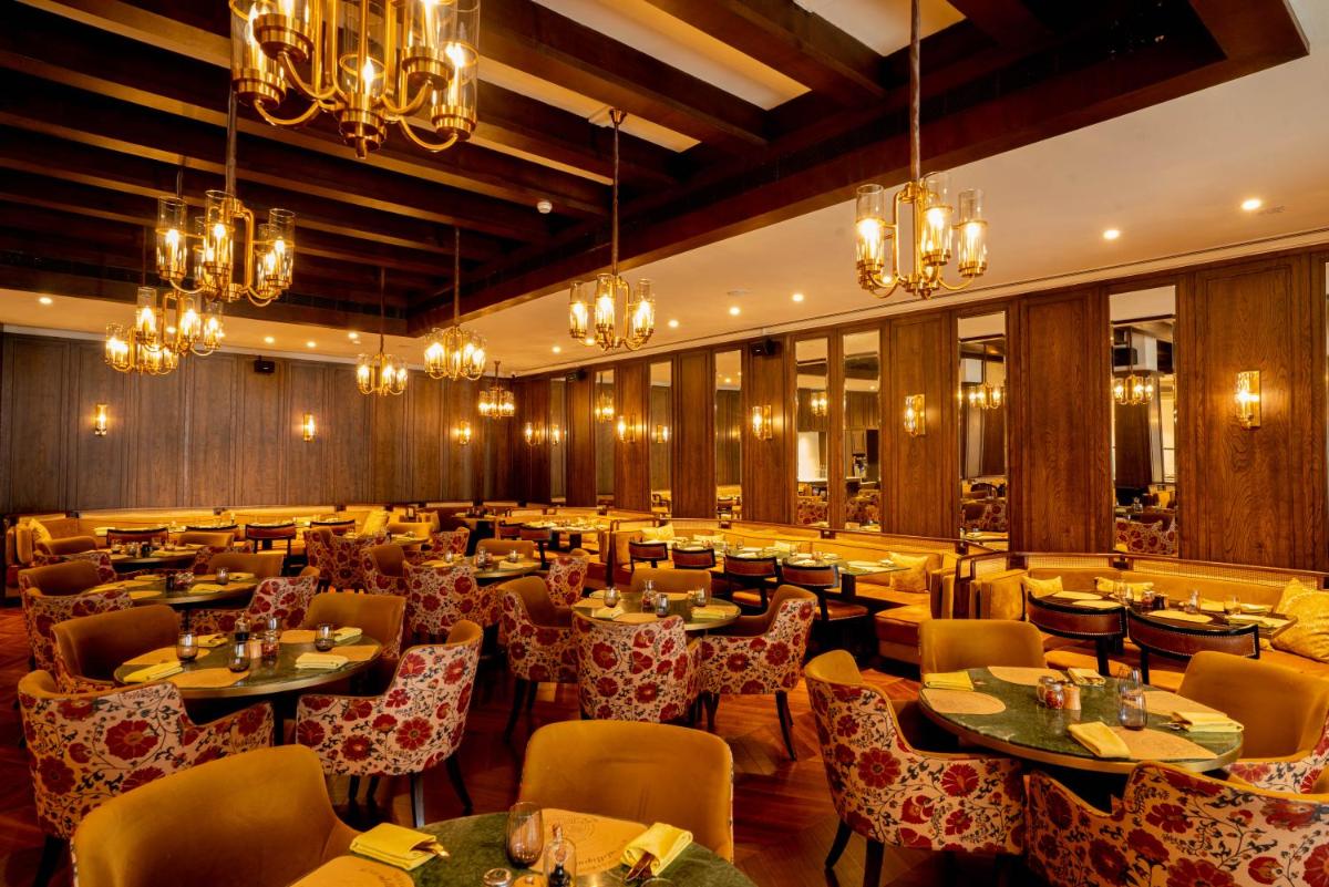 a restaurant with tables and chairs and chandeliers at President - IHCL SeleQtions in Mumbai