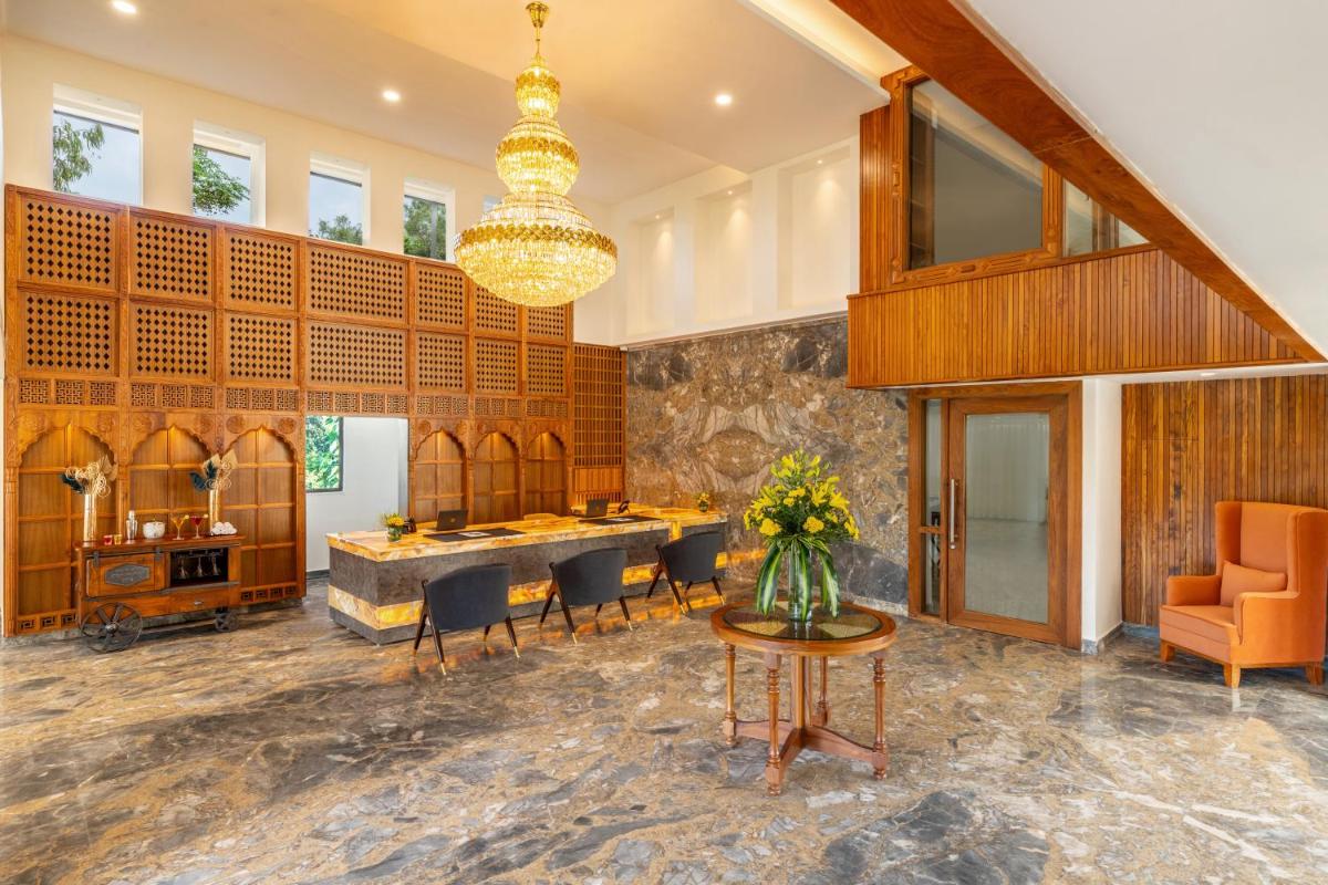 a lobby with a table and chairs and a chandelier at The Prominence Mussoorie Road Dehradun in Dehradun
