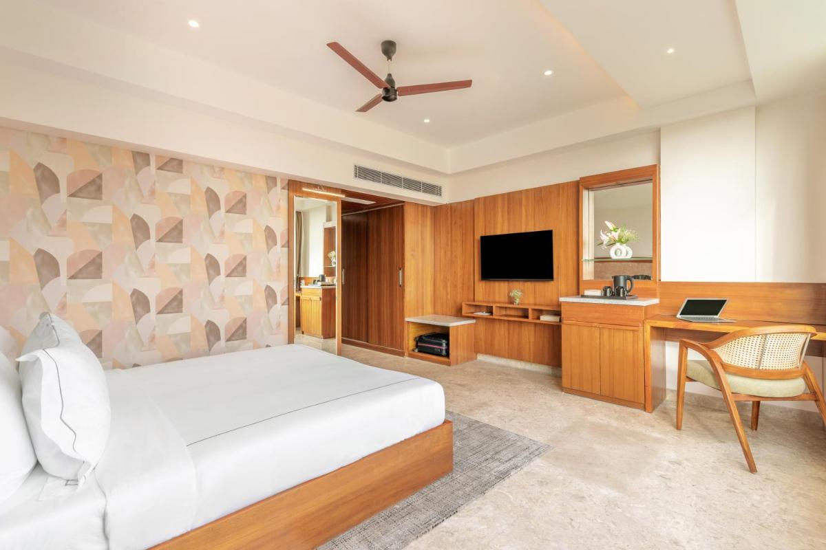a bedroom with a bed and a desk and a television at The Prominence Mussoorie Road Dehradun in Dehradun