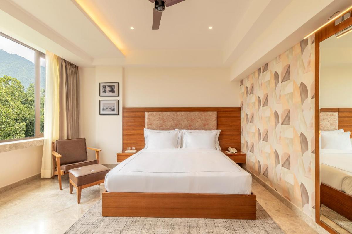 a hotel room with a bed and a chair at The Prominence Mussoorie Road Dehradun in Dehradun