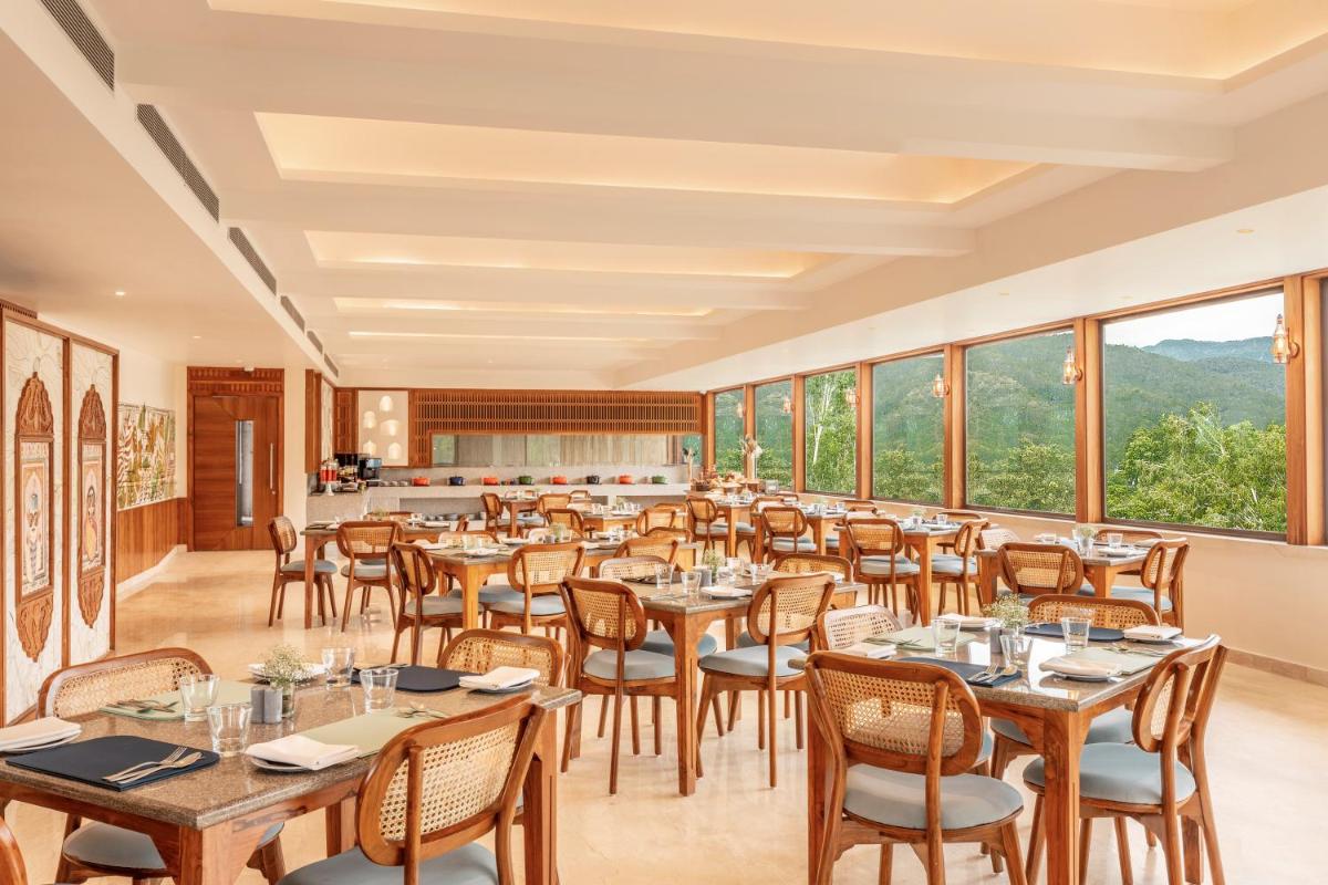 a restaurant with tables and chairs and large windows at The Prominence Mussoorie Road Dehradun in Dehradun
