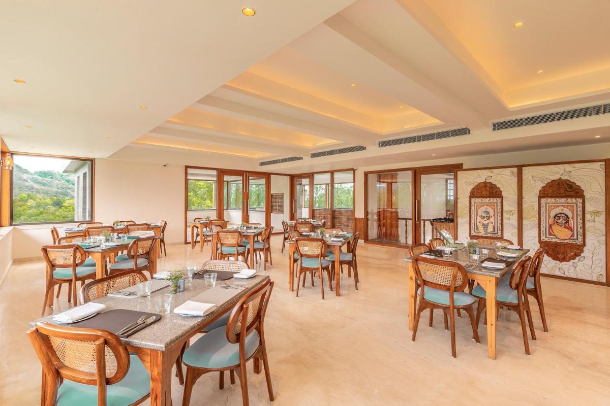 a restaurant with tables and chairs and windows at The Prominence Mussoorie Road Dehradun in Dehradun