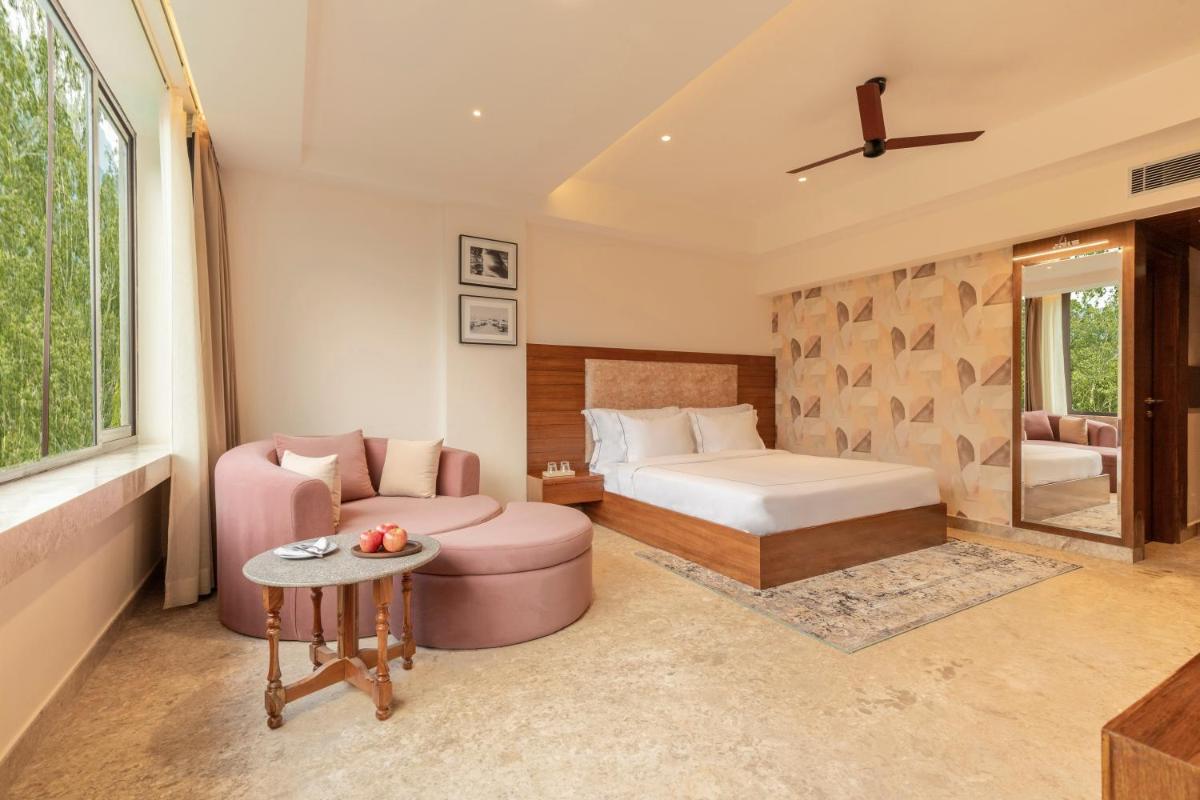 a bedroom with a bed and a couch and a table at The Prominence Mussoorie Road Dehradun in Dehradun