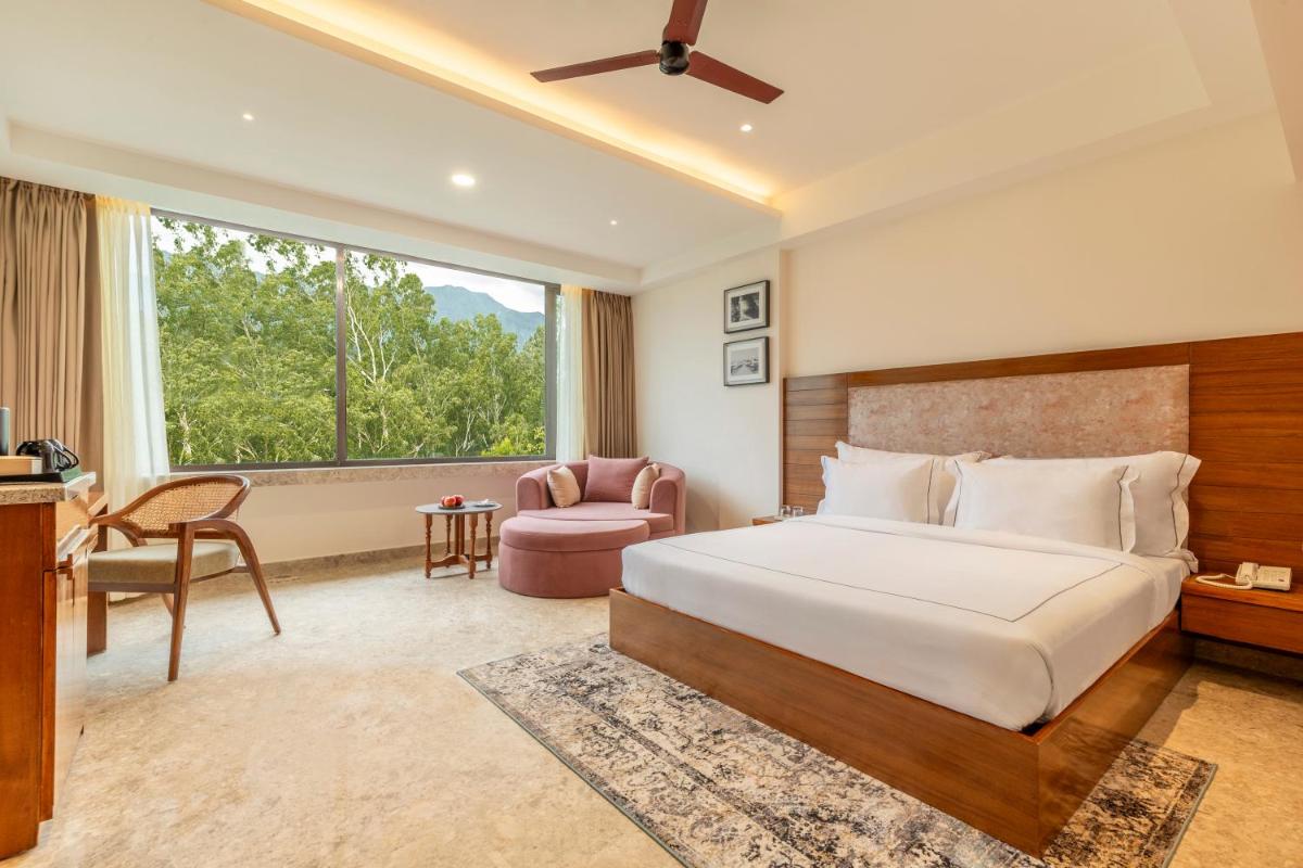 a bedroom with a bed and a chair and a window at The Prominence Mussoorie Road Dehradun in Dehradun