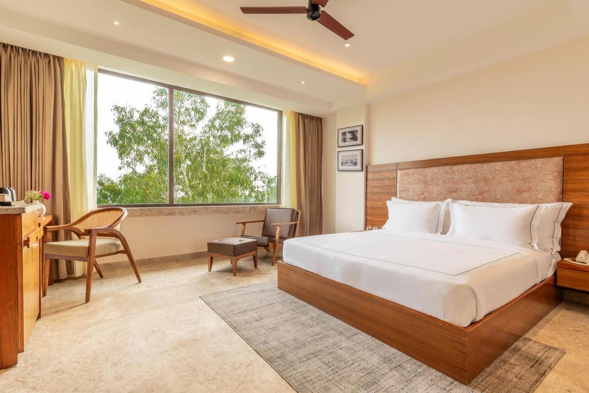 a bedroom with a bed and a desk and a window at The Prominence Mussoorie Road Dehradun in Dehradun
