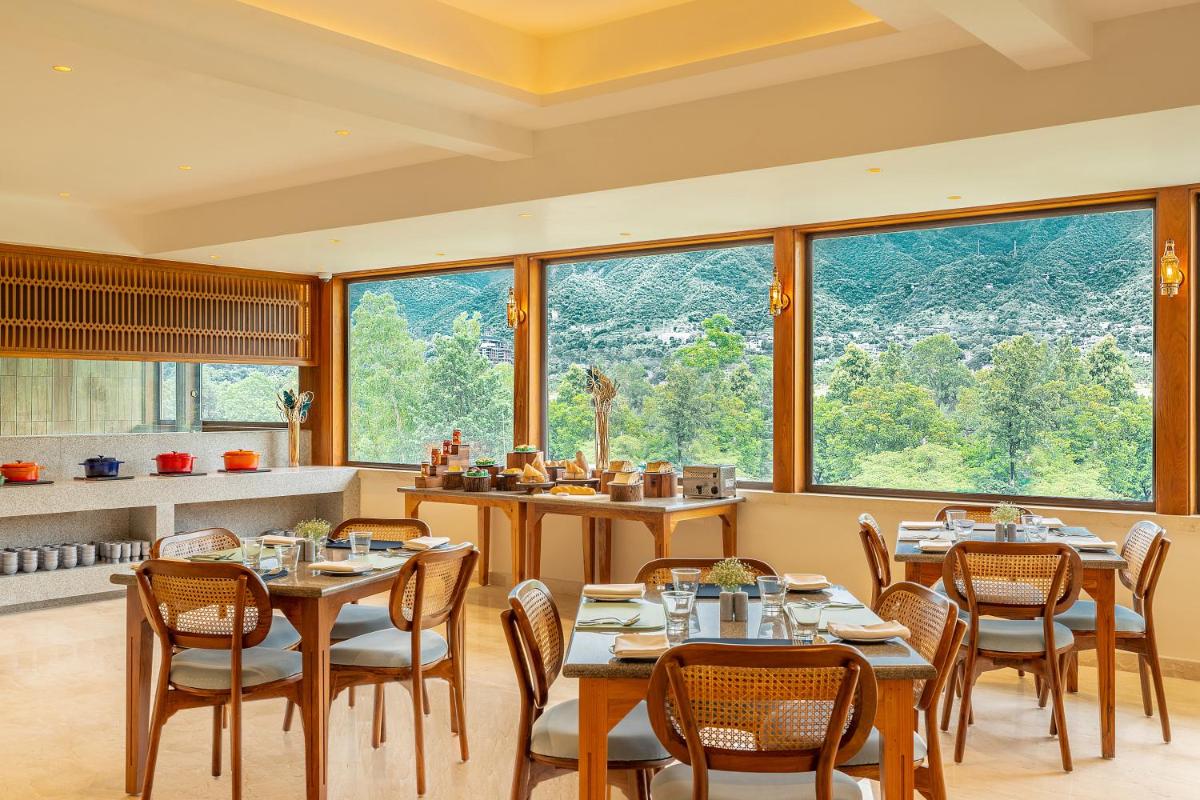 a restaurant with tables and chairs and large windows at The Prominence Mussoorie Road Dehradun in Dehradun