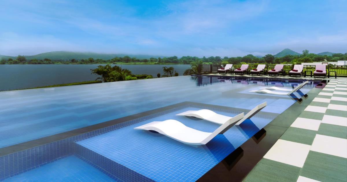 a swimming pool with lounge chairs on a resort at ZANA Lakeview Resort - most scenic lakeside resort in Udaipur