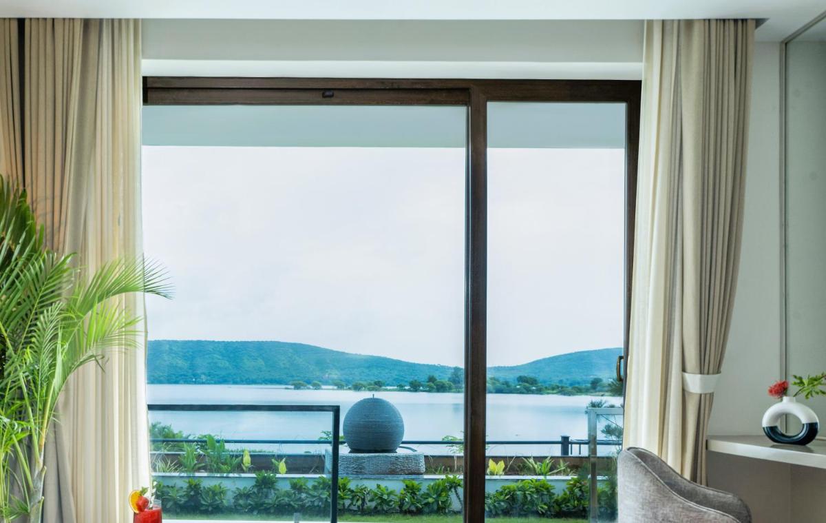 a living room with a view of the water at ZANA Lakeview Resort - most scenic lakeside resort in Udaipur