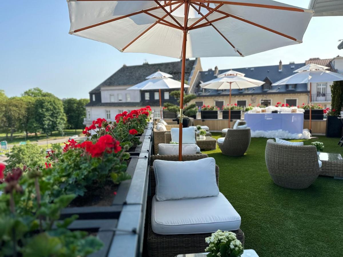 un patio avec des chaises, un parasol et des fleurs dans l'établissement Best Western Plus Thionville Centre, à Thionville