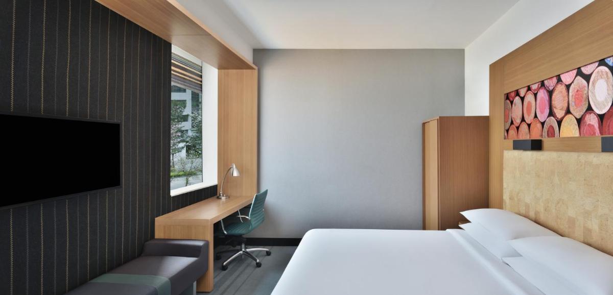 a hotel room with a bed and a desk and a tv at Aloft Bengaluru Outer Ring Road in Bengaluru