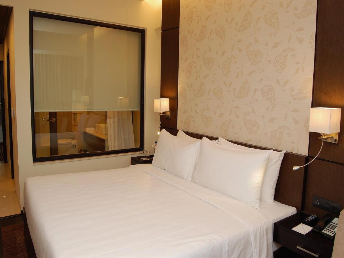 a bedroom with a large white bed with a large mirror at Sunday Hotel Jaipur in Jaipur