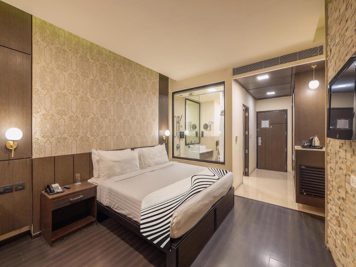 a bedroom with a large bed and a bathroom at Sunday Hotel Jaipur in Jaipur