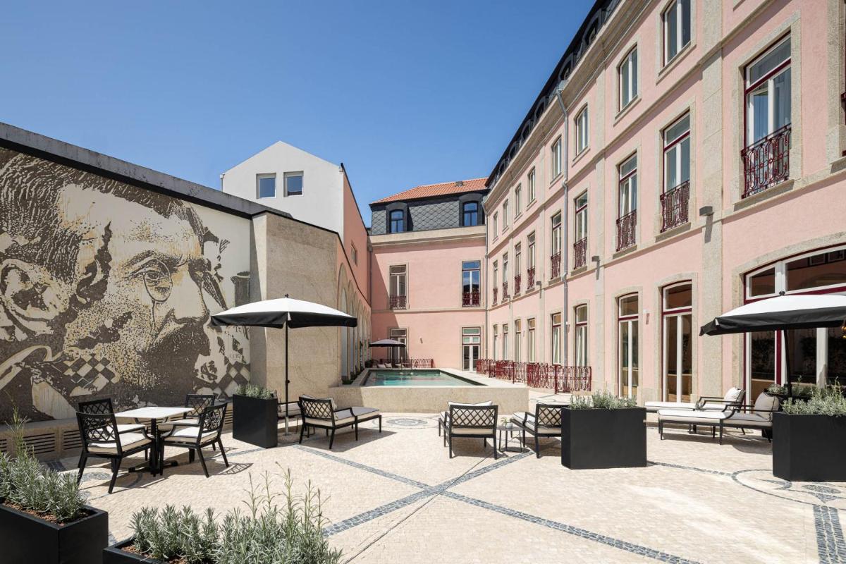 um pátio com mesas e cadeiras e um mural de uma mulher em MS Collection Aveiro - Palacete Valdemouro em Aveiro