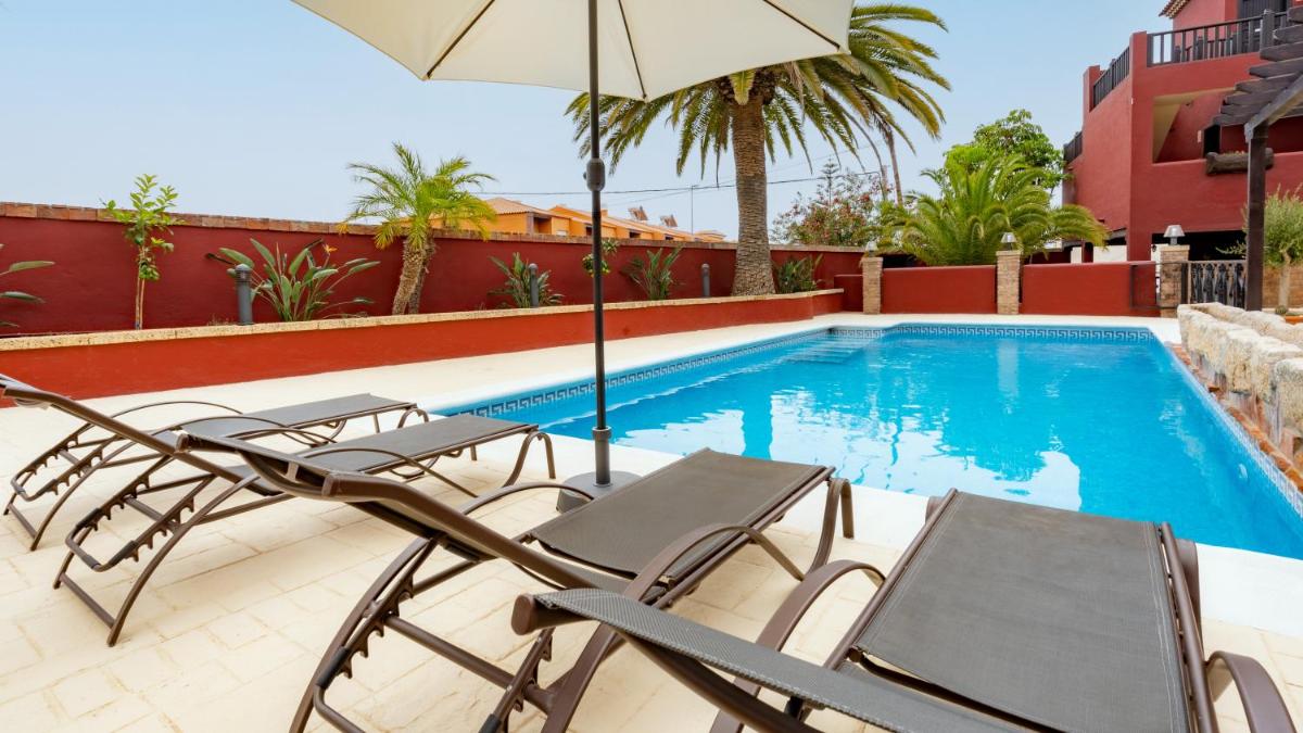 Un patio con sillas y sombrilla y una piscina. en Hotel Ecolife Tenerife, en San Miguel de Abona