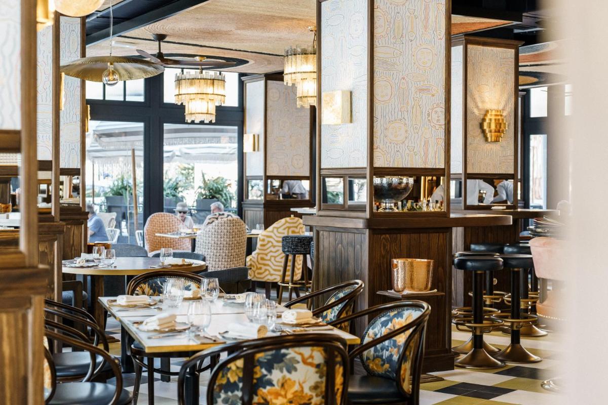 Un restaurante con mesas y sillas y gente al fondo. en Hotel MS Maestranza Málaga, en Málaga