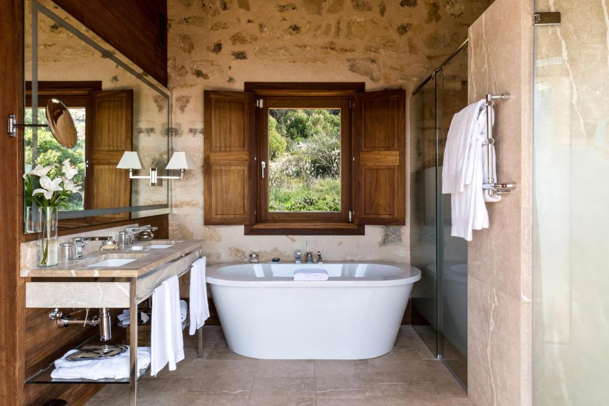 Un baño con bañera, lavabo y ventana. en Cap Rocat, a Small Luxury Hotel of the World, en Cala Blava