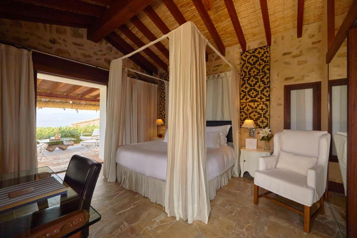 Un dormitorio con una cama, un escritorio y una silla. en Cap Rocat, a Small Luxury Hotel of the World, en Cala Blava