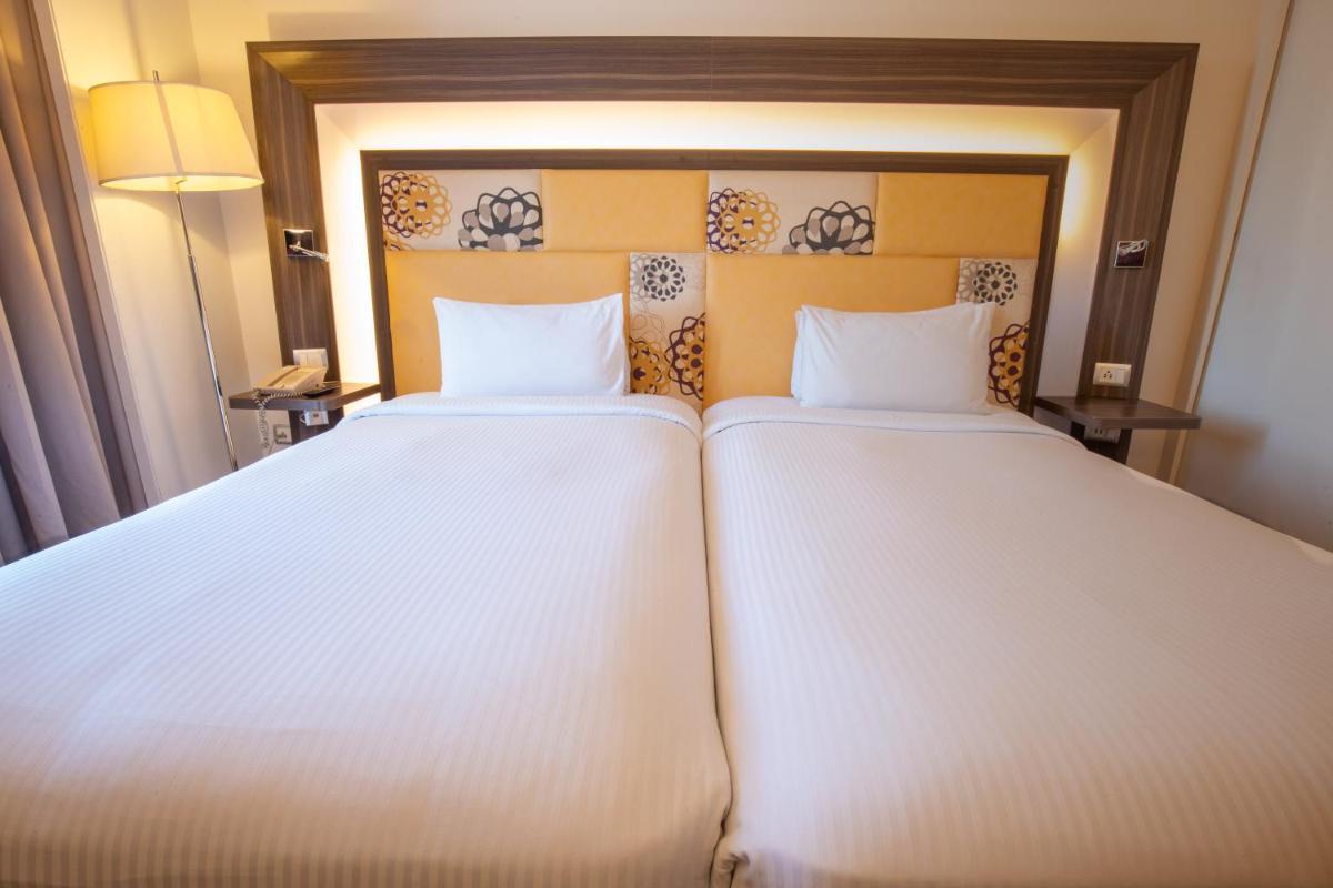 two beds in a hotel room with white sheets at Novotel Pune Viman Nagar Road in Pune