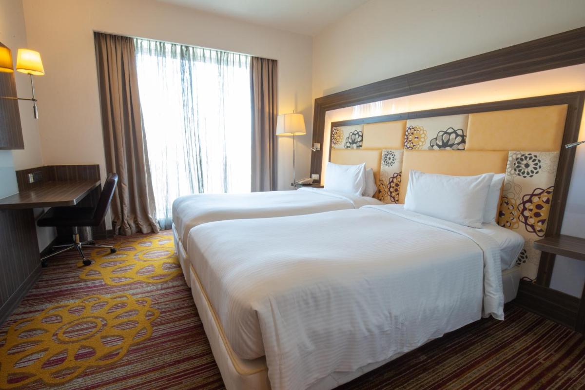 a large hotel room with two beds and a desk at Novotel Pune Viman Nagar Road in Pune