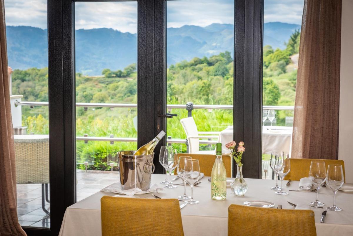 una mesa con copas de vino y vistas a las montañas en Hosteria de Torazo Nature Hotel & Spa, en Torazo