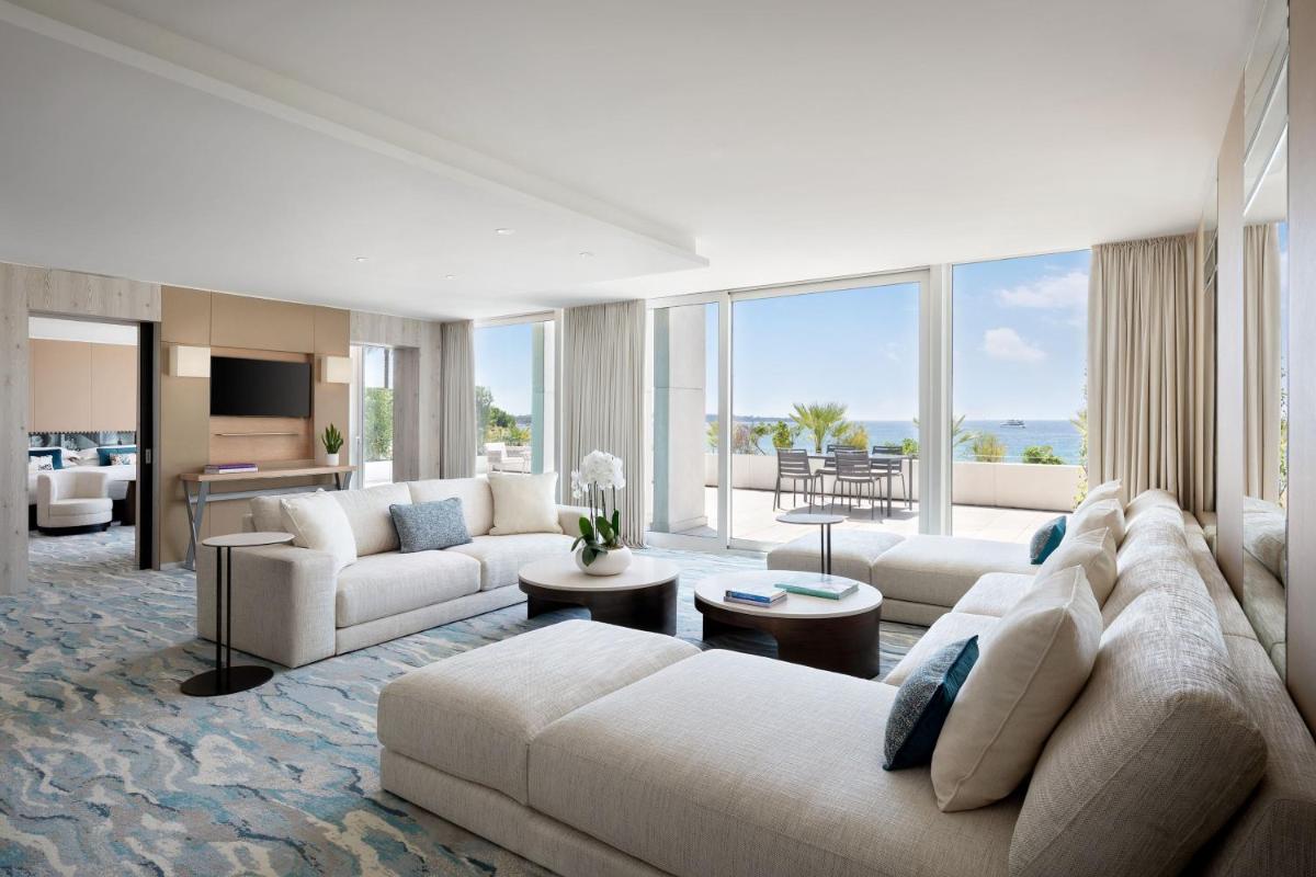 un salon avec des meubles blancs et une grande fenêtre dans l'établissement JW Marriott Cannes, à Cannes