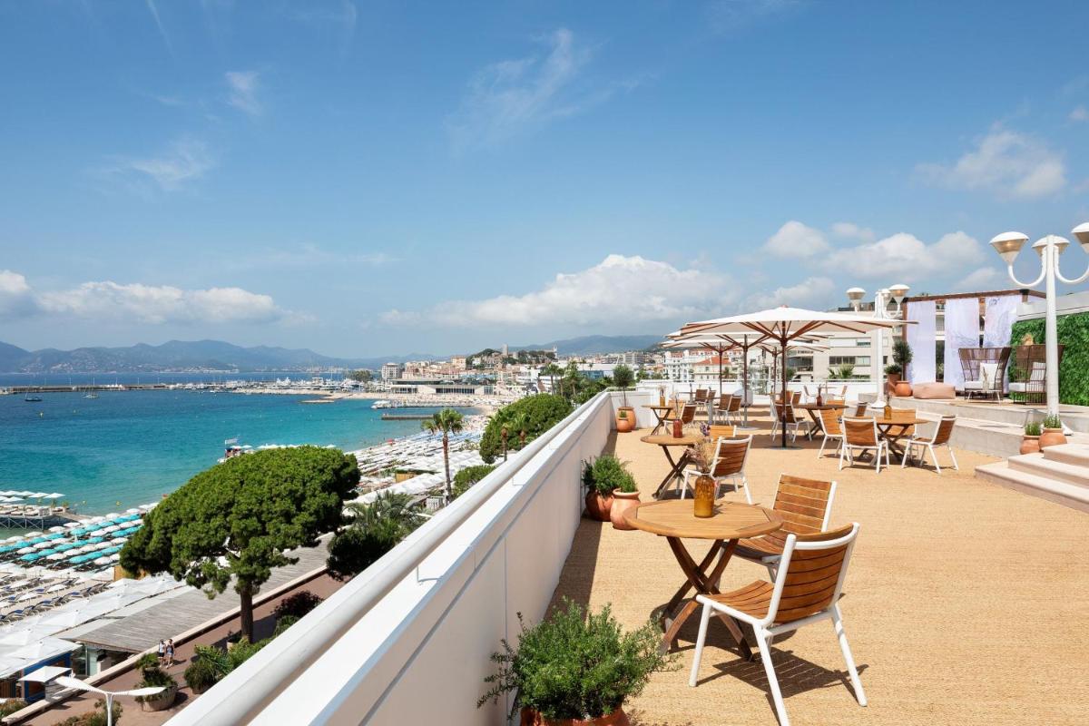 d'un balcon avec des tables et des chaises et une vue sur l'océan. dans l'établissement JW Marriott Cannes, à Cannes