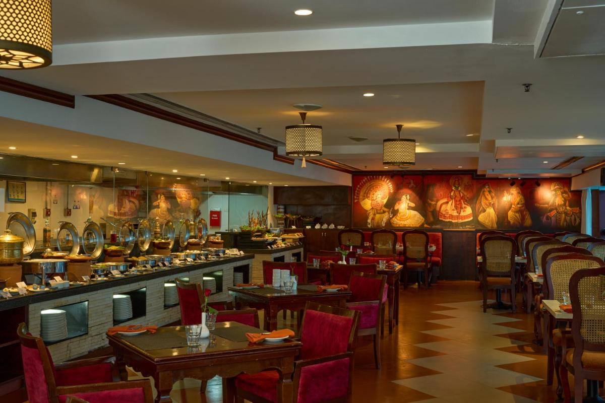 a restaurant with tables and chairs and a bar at The Raviz Calicut in Kozhikode