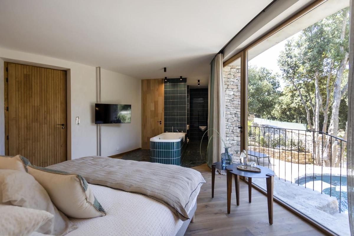 - une chambre avec un lit et un balcon avec une baignoire dans l'établissement A SPERANZA Suites avec piscine privative chauffée, à Bonifacio