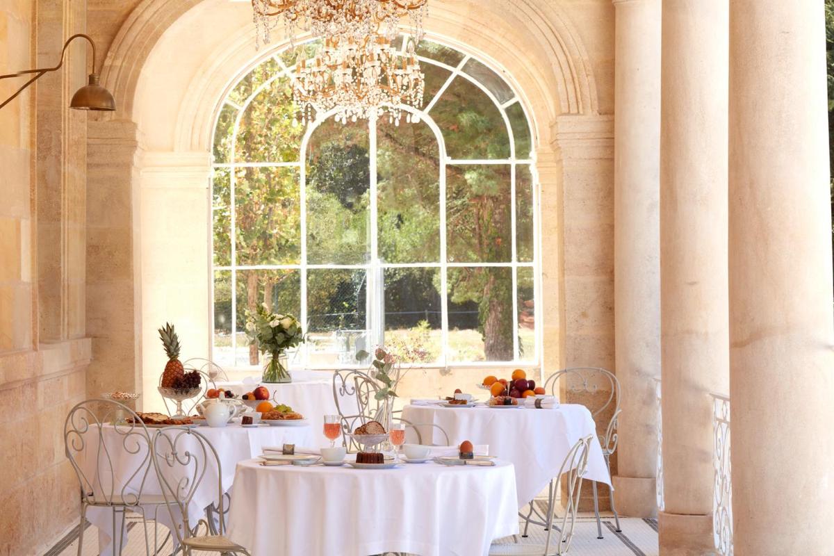 une salle à manger avec des tables blanches et une grande fenêtre dans l'établissement Château Léognan, Domaine viticole - proche Bordeaux, à Léognan