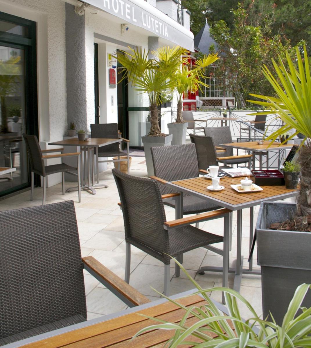 un patio extérieur avec tables, chaises et plantes dans l'établissement Hôtel Lutétia & Spa, à La Baule