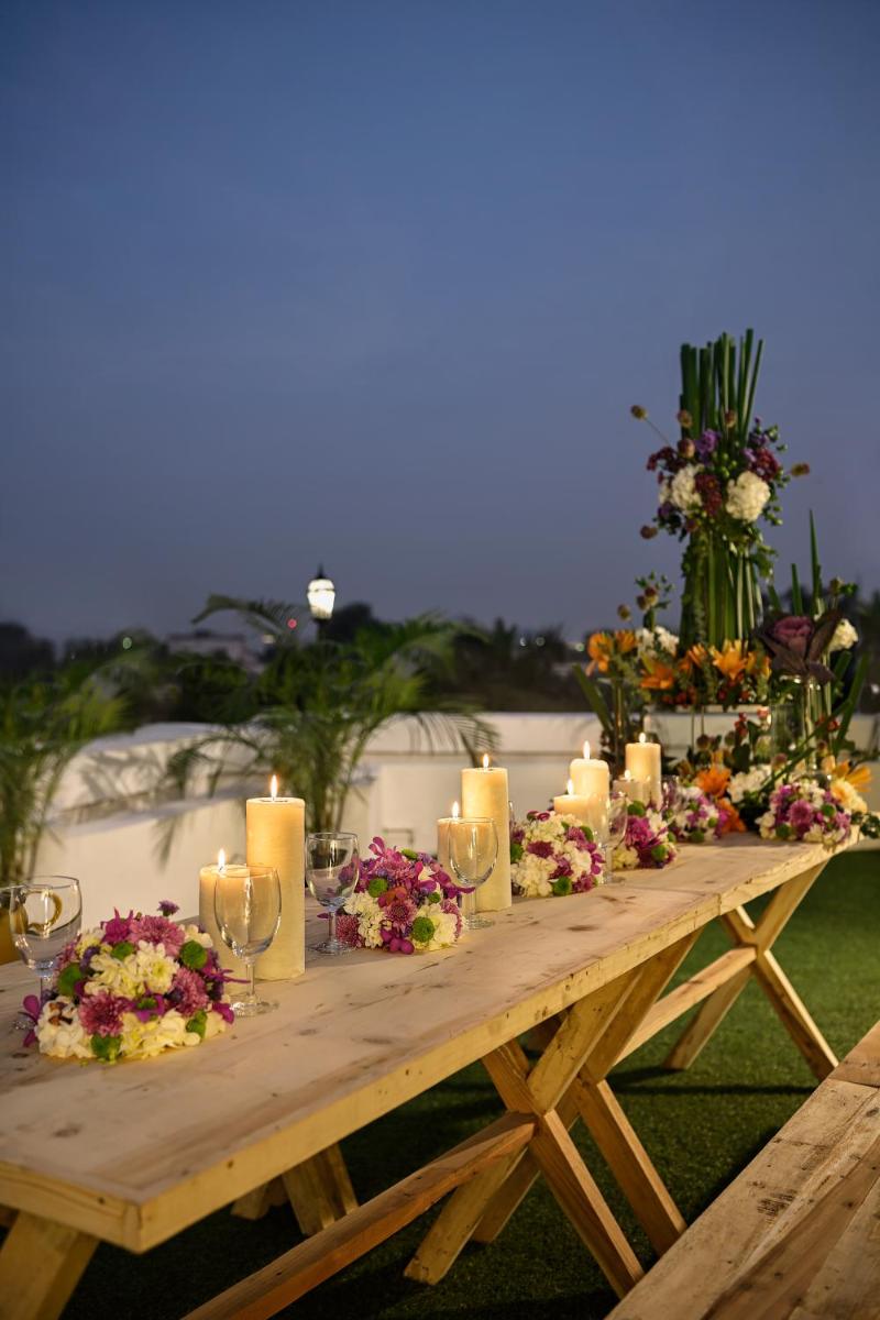 a wooden table with candles and flowers on it at Ambassador, New Delhi - IHCL SeleQtions in New Delhi a wooden table with candles and flowers on it at Ambassador, New Delhi - IHCL SeleQtions in New Delhi