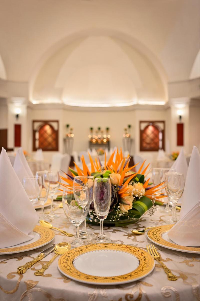 a table with plates and glasses and flowers on it at Ambassador, New Delhi - IHCL SeleQtions in New Delhi a table with plates and glasses and flowers on it at Ambassador, New Delhi - IHCL SeleQtions in New Delhi